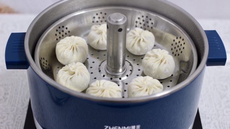 冬日暖心菜 鸡肉黄瓜胡萝卜包,臻米升降火锅,倒入适量清水后,大火煮沸,打开升降功能,把蒸屉篮升起来,把包好的包子放入屉篮里。