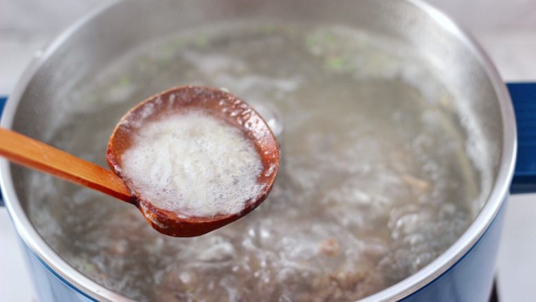 冬日暖心菜 手工牛肉丸子粉丝双色萝卜煲,用勺子撇去浮末。