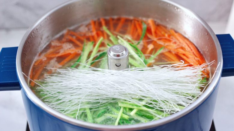 冬日暖心菜 手工牛肉丸子粉丝双色萝卜煲,再把升降篮降到底,大火再次煮沸锅中的汤,加入煮熟的一半丸子,上面再加入青萝卜丝和胡萝卜丝,<a style='color:red;display:inline-block;' href='/shicai/ 523'>粉丝</a>洗净后也放入锅中。