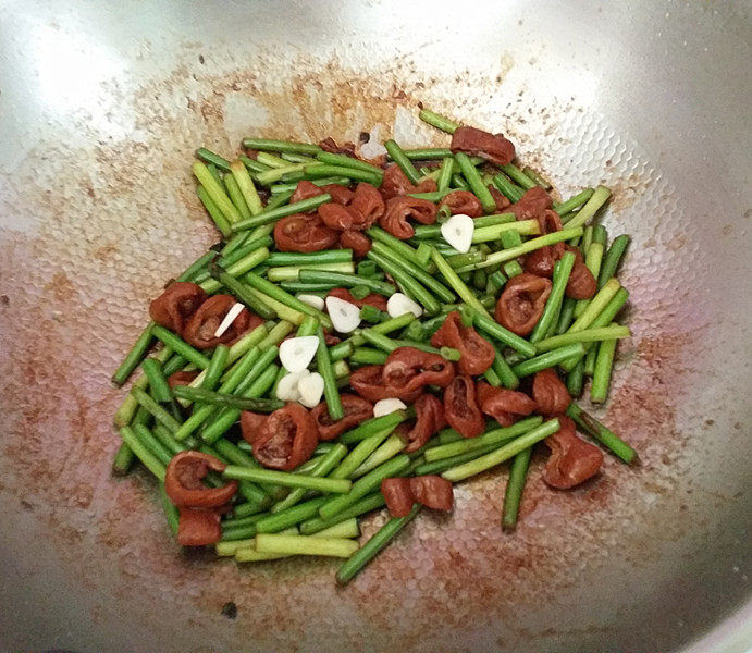 干煸肥肠,最后将余下的蒜片撒入,炒匀关火
