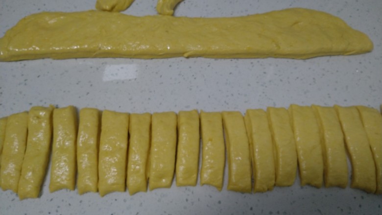 南瓜油条,操作台上均匀涂上食用油,将面团整理成长条状,一分为2,均匀切成2根手指的宽度