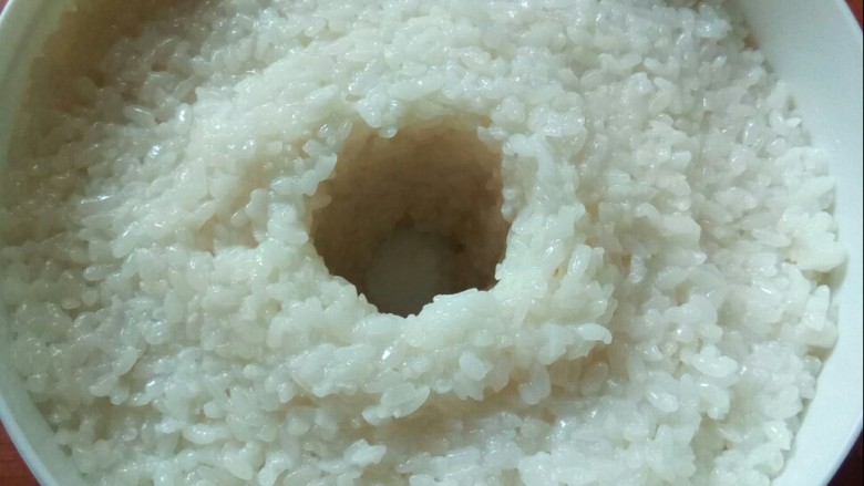 醪糟,将拌匀的糯米放入容器中,压实,中间挖洞。