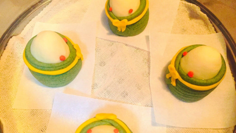 幼粽小馒头,再取黄面条做领结点缀,用白面搓球黏在脸颊,画笔沾红色素上色