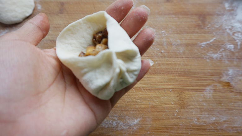 香菇卤肉丁包,包子皮放上馅料,依次捏出包子褶。