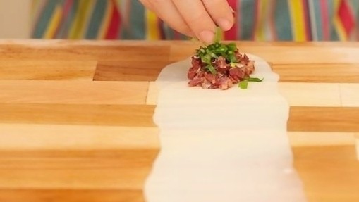 香酥牛肉饼,在面皮的一端放上适量的牛肉馅,再在上面撒上适量的青葱末