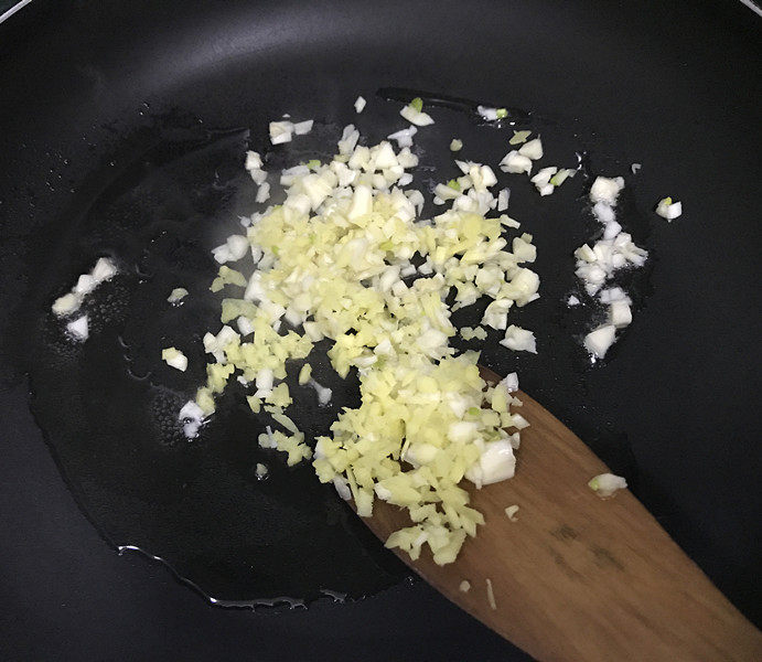 蒜蓉粉丝蒸生蚝,现在来炒蒜蓉:炒锅烧至微微热,倒些食用油,下入姜米和2/3蒜末