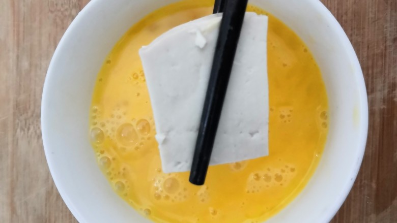 鱼香脆皮豆腐,把切块的豆腐,放入鸡蛋液中,让鸡蛋液,粘满豆腐
