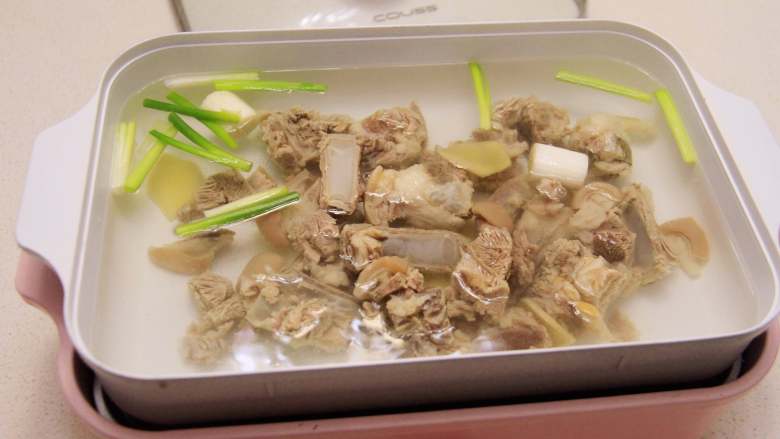 羊肉炖萝卜汤,将深盘清洗后重新加入开水,倒入焯好的羊肉,放香葱段、姜片,大葱段(八角、桂皮、香叶可选用),放一勺白酒,加盖后开最大火煮沸腾,然后转中火慢炖约1小时。