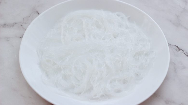 金蒜粉丝蒸海虾,取一个大一点的盘子,把泡发好的粉丝,沥干水分码放在盘中。