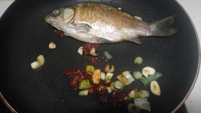 红烧鲫鱼炖冻内脂豆腐、粉皮,翻面煎至两面金黄,放入蒜、葱、豆瓣酱炒香