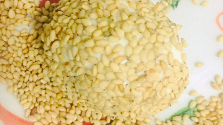 红豆麻团,表变沾水后包裹一层芝麻,放手中轻轻按压,这样炸的时候不易脱落