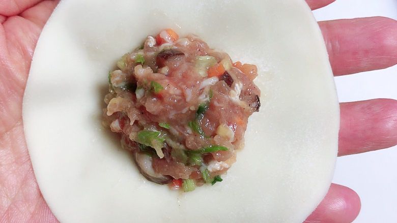 冬至美食 喜庆四喜蒸饺,取饺子皮,将皮稍微擀大一些,大约是原饺子皮的1.5倍大小即可。饺子皮中放入馅儿。
