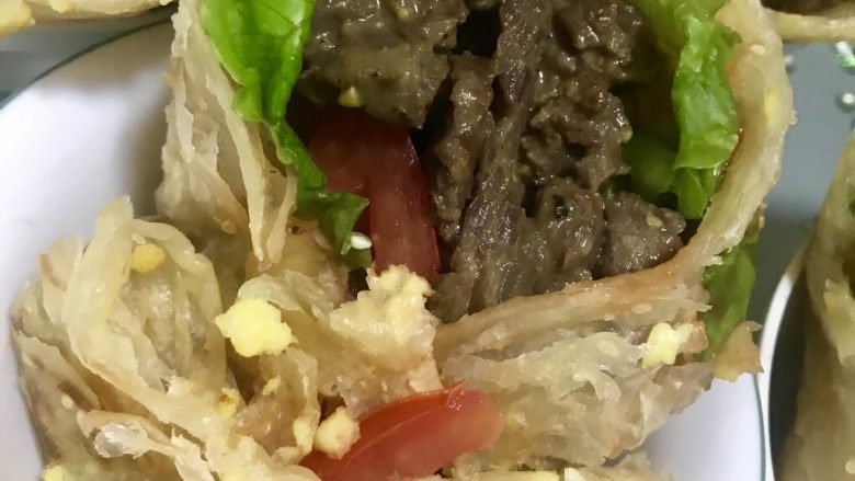 嫩牛五方,煎好的手抓饼涂一层<a style='color:red;display:inline-block;' href='/shicai/ 699'>番茄酱</a>，依次铺上生菜番茄青椒和牛肉，尽量都铺在中间