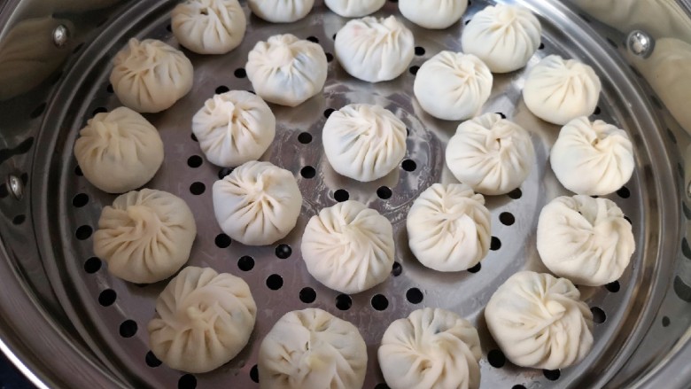冬至美食 饺子皮小笼包,蒸锅内放水,篦子上刷上一层食用油,放上包好的小笼包。