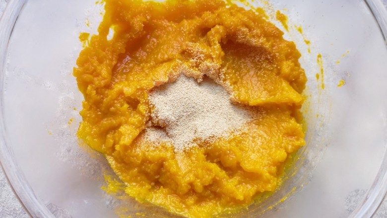冬至美食 南瓜豆角馅包子,蒸熟的南瓜片从蒸锅里取出,放入盆里用勺子压成南瓜泥,晾至温热加入<a style='color:red;display:inline-block;' href='/shicai/ 739'>发酵粉</a>搅拌均匀。