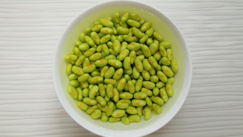 冬至美食 毛豆炒鸡丁,将剥好的豆子放入水里,用手轻轻的搓一下,洗去<a style='color:red;display:inline-block;' href='/shicai/ 67'>毛豆</a>上面一层像膜一样的东西,控一下水分备用。