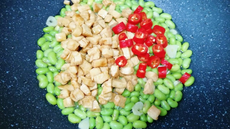 冬至美食 毛豆炒鸡丁,下入炒好的鸡丁和红线椒翻炒均匀。