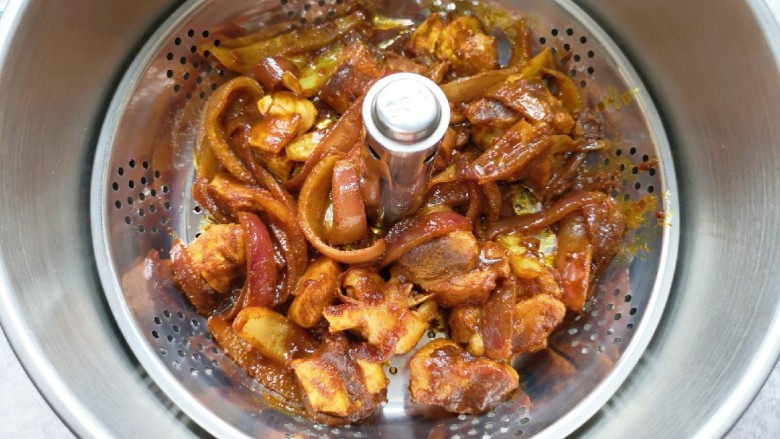 冬至美食 咖喱丸子火锅,将炒好的洋葱和鸡腿块一起放进升降火锅的提篮里,加水没过提篮。