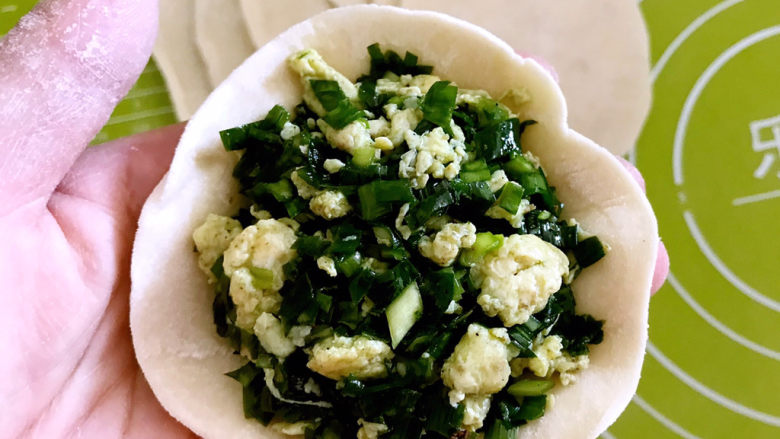 鸡蛋韭菜盒子,取一个饺子皮,加入2勺馅料