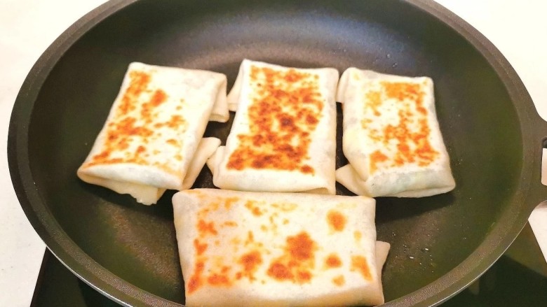 鸡蛋韭菜盒子,油锅温热,把韭菜盒坯子放到锅里烙1分钟,不要盖盖子,然后翻面,再烙1分钟