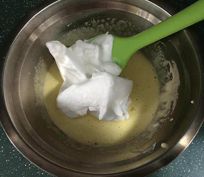 草莓欧蕾,取1/3的蛋白霜到蛋黄盆中,用刮刀快速地上下翻拌均匀;然后再将剩余的蛋白霜,一起倒入蛋黄糊中,用同样的方法拌匀