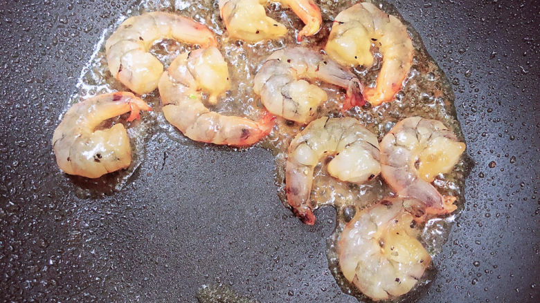 菠萝虾仁炒饭,锅中倒入油,烧至五成热,放入虾仁煎煮虾仁变成黄色。