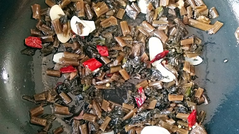 雪菜肉丝面,锅中适量油烧热后将蒜片干辣椒下锅爆出香味,然后下入雪菜翻炒均匀盛出备用。(这里也可将之前炒好的肉丝回锅和雪菜一起翻炒均匀)