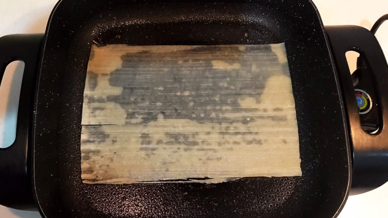 东北烤冷面,炒锅刷一层大豆色拉油,加入一片冷面,在冷面四周撒一点冷水,免得冷面四边打卷,小火煎制