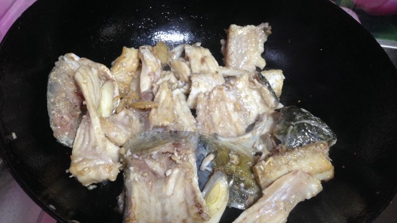 老坛酸菜鱼,锅里放油炒香葱姜蒜,下入鱼头鱼尾鱼骨头等炒一分钟