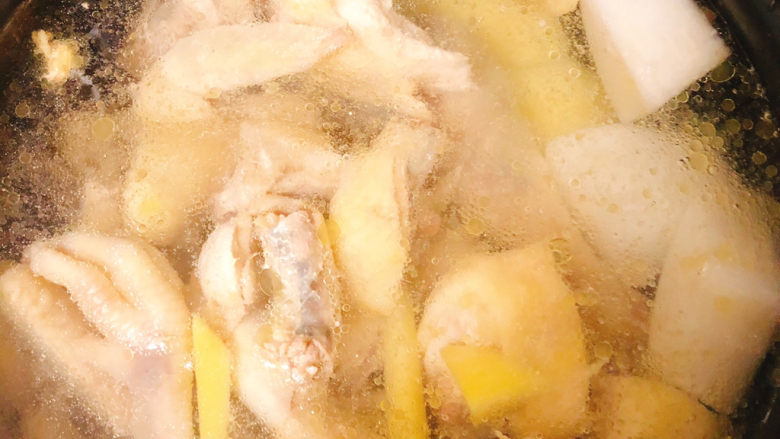 冬日暖身鸡汤,焯好水的鸡放入电饭锅中,锅中加入适量水同时放入土豆白萝卜一起煮