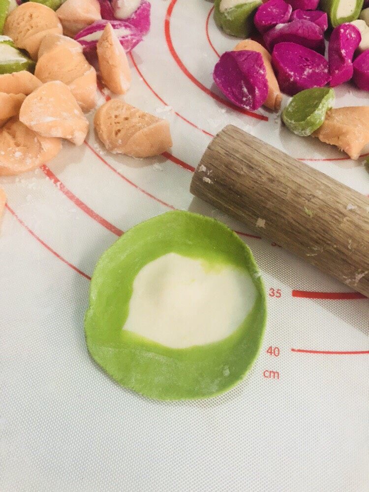 彩色水饺,每个都擀成近圆形薄片。记得撒点面粉在面皮上,避免互相粘连。