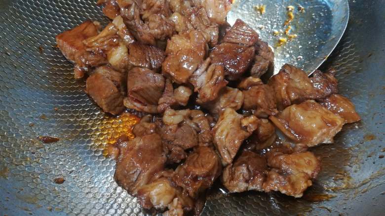 土豆牛腩煲,糖色炒好了以后,放入焯过水的牛腩块。翻炒一两分钟,让每一个肉粒都裹上糖浆。
