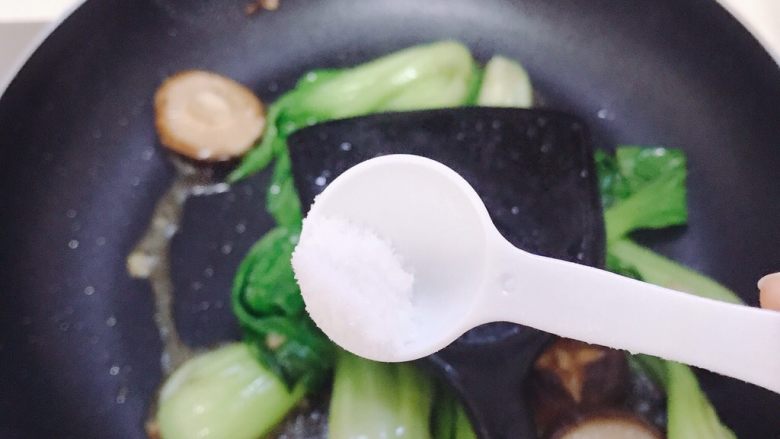 青菜炒香菇,青菜变色后,加少许盐调味。