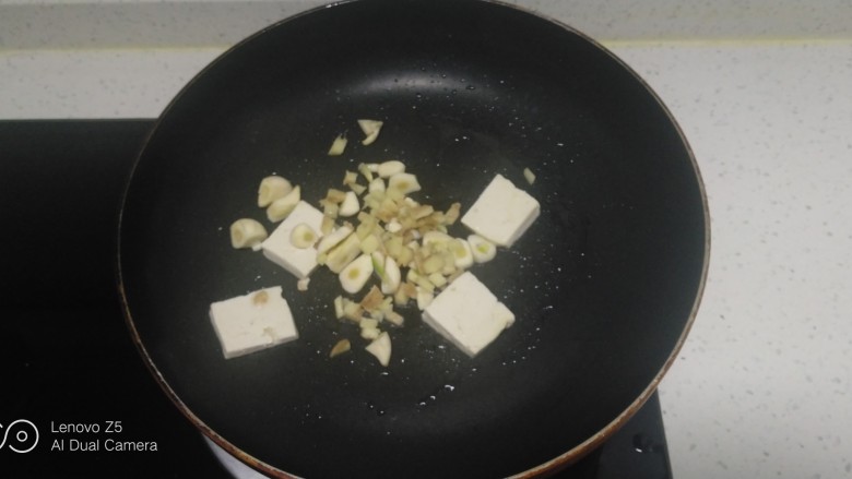 豆腐炒上海青、豆腐皮、平菇,锅中放入适量油,放入豆腐、蒜瓣、姜末