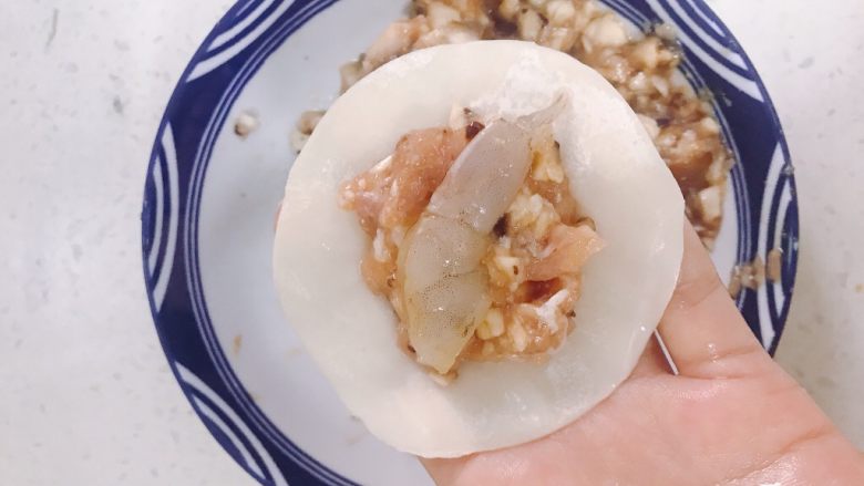 香菇虾仁饺子,取一张<a style='color:red;display:inline-block;' href='/shicai/ 4346'>饺子皮</a>放入香菇猪肉馅,在中间放上一块虾仁再包起来。