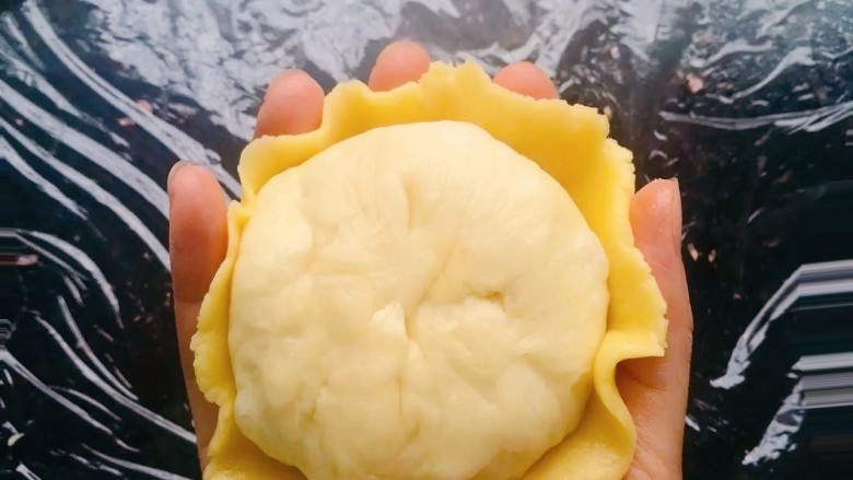 菠萝面包,把压成薄饼状的菠萝皮轻轻移到手掌心,放入包了菠萝馅的面团、把边边的菠萝皮往面团里收一收即可