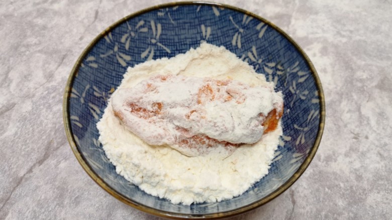 香酥炸鸡翅,先将腌好的鸡翅放入玉米淀粉里面,表面粘上一层玉米淀粉。