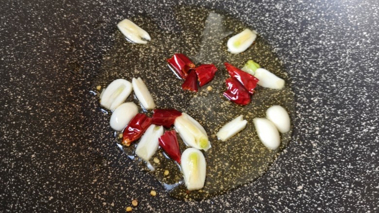 醋溜西葫芦,炒锅内倒入适量的食用油烧热,下入蒜片和干红辣椒炒香。