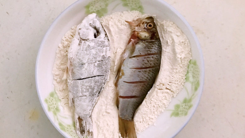 香煎鲫鱼,把鲫鱼放入面粉中打个滚,让鲫鱼均匀的裹上一层薄薄的面粉