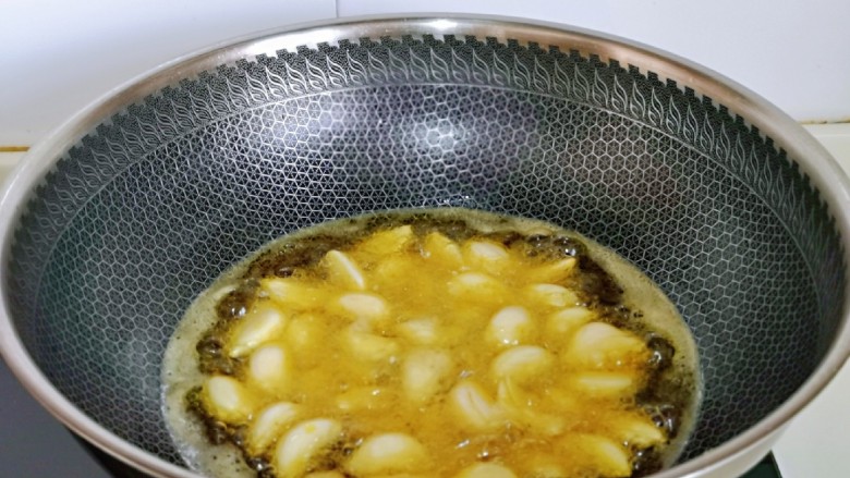 葱爆羊肉片,起油锅,油温6成热时加入蒜瓣。