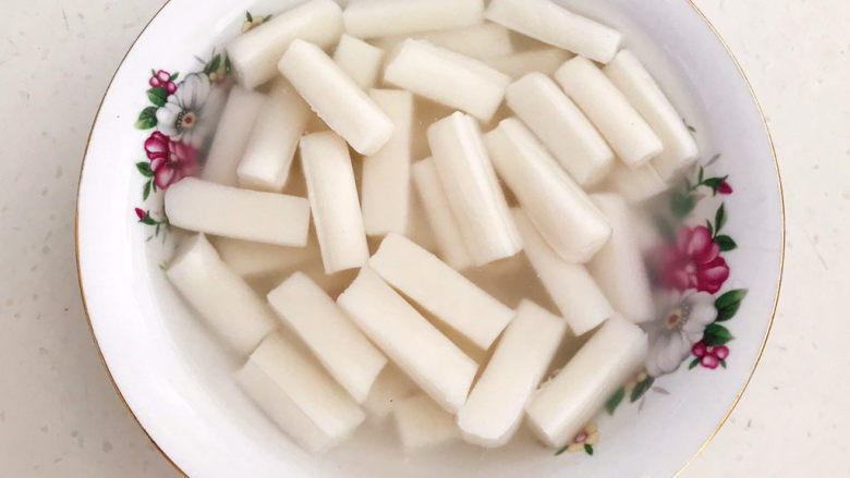 鸡蛋炒年糕,把煮好的年糕捞出来放入碗里,加入少许凉开水,免得煮好的年糕粘在一起