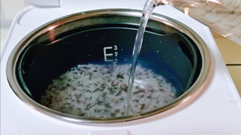 黑米红豆粥,掏干净的米倒入饭煲中,再加入纯净水,水量根据用米的量来。