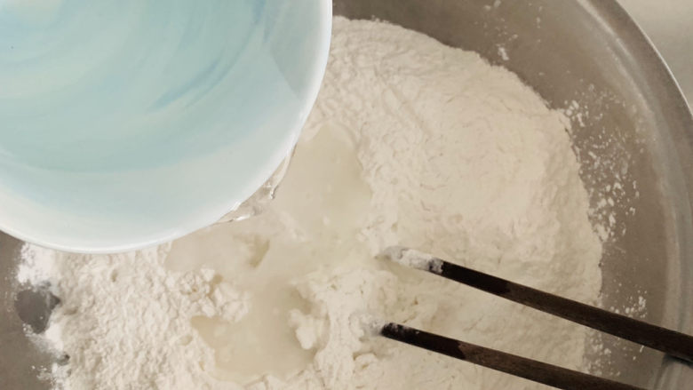 红豆汤圆,面粉的吸水量不一样,请先预留10克。
将水倒入糯米粉中,用筷子搅拌。