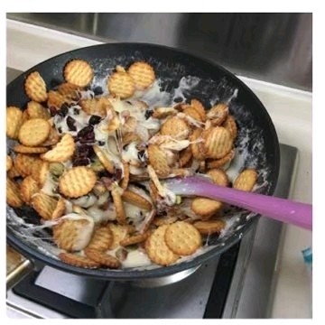 开心雪花酥〈快手版〉,先加入蔓越莓干和开心果,再加入小圆饼,关火搅拌均匀。