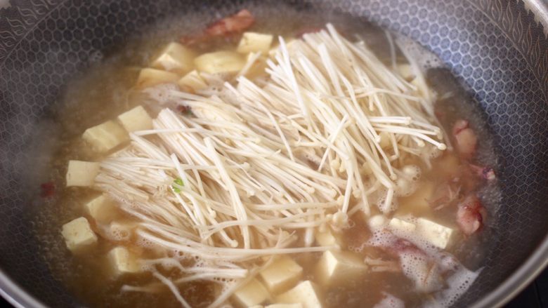 金针菇豆腐鱿鱼煲,大火烧开后炖煮5分钟左右,加入金针菇。