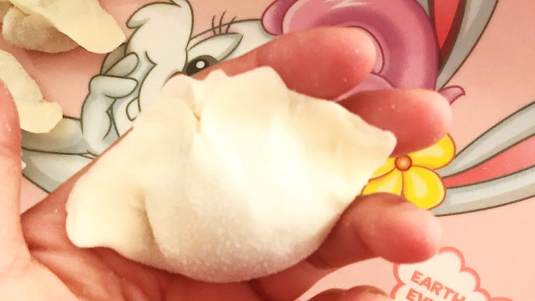 玉米猪肉饺,取一个饺子皮,加入1勺玉米猪肉馅料,边缘捏紧,一个饺子就包好了