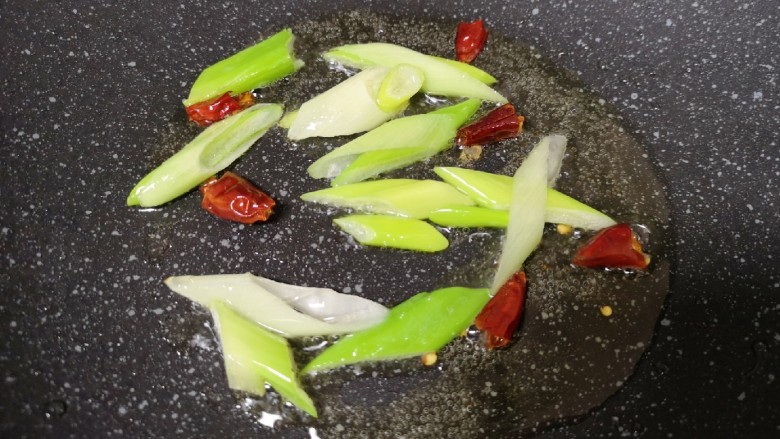 芹菜炒牛肉,锅底留余油,下入葱和干红辣椒炒香。