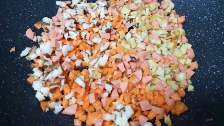 玉米面糊糊,不粘锅内倒少许食用油烧热,下入香菇、胡萝卜、豆腐干和火腿肠。
