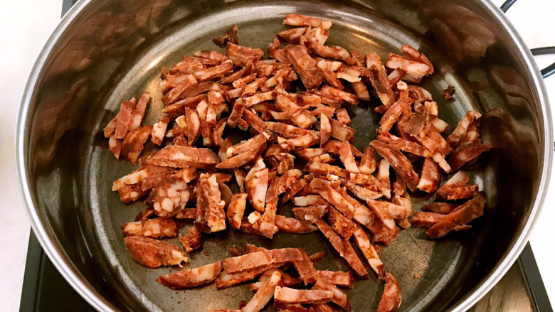 香菇腊肠焖饭,另起锅,加入1小勺大豆色拉油,炒锅烧热后加入腊肠条,小火煸炒1分钟