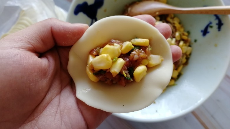 玉米猪肉饺,拿出一张饺皮,放上适量的馅儿